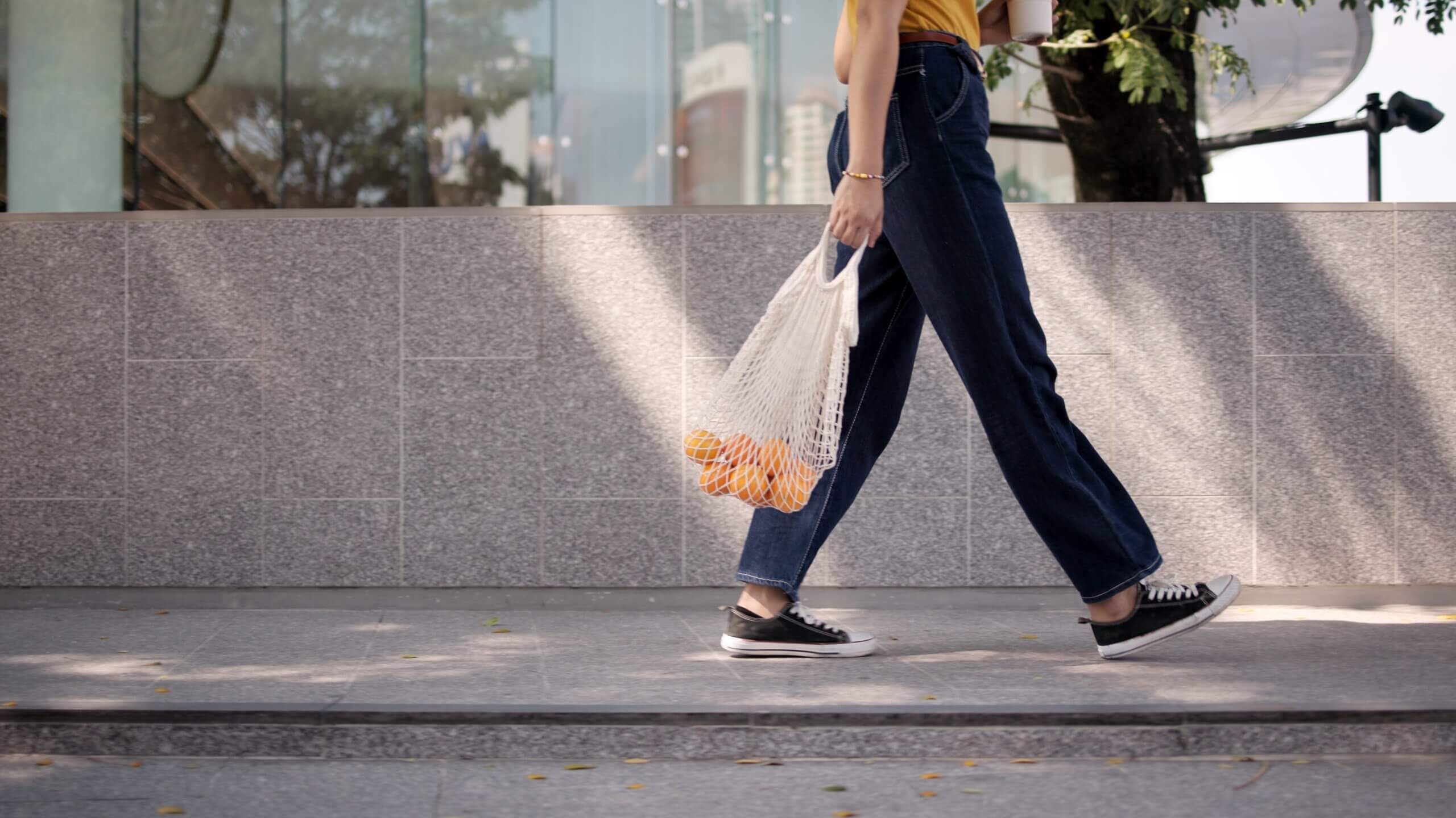 Woman walking with oranges in a knit bag