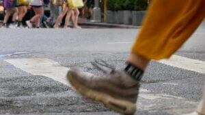 Close-up of a person in motion wearing yellow pants stepping on a crosswalk.