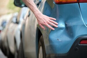 hit and run lawyer A close-up of a blue car's rear bumper showing a dent and scratches.