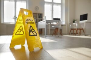 Señal de precaución por piso mojado en un espacio de coworking.