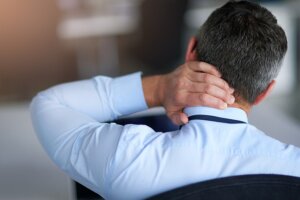  man holding the back of his neck from a headache after a car accident.