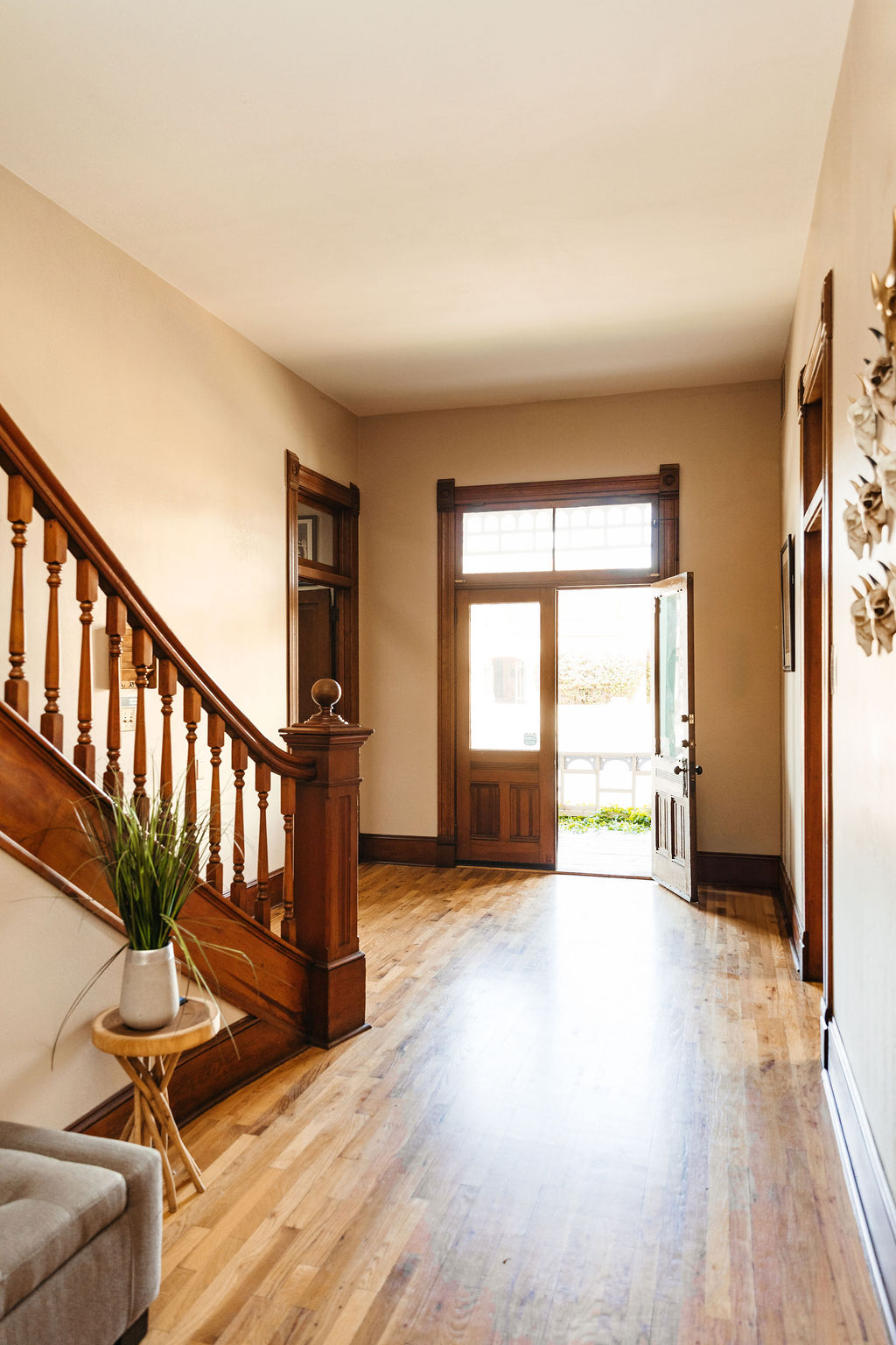 Una entrada con suelos de madera, una escalera de madera y una puerta principal abierta que conduce a un porche, que se menciona en nuestras preguntas frecuentes.