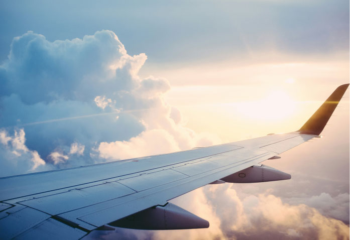 Airplane wing seen from a window flying above a sea of clouds at sunset, a view that invites reflection on personal injury recovery.