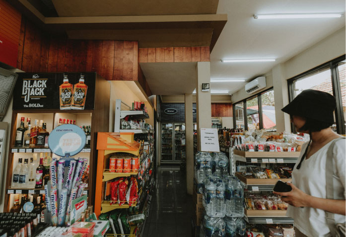 A person shops in the aisle of a small convenience store stocked with snacks, beverages, and liquor, a setting often relevant to personal injury claims.