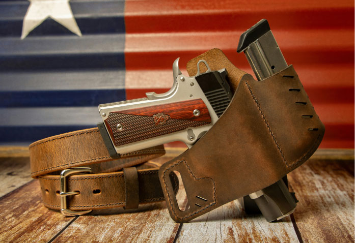 A handgun with wooden grips in a leather holster attached to a matching leather belt, with an extra magazine visible, items often associated with personal injury risks.