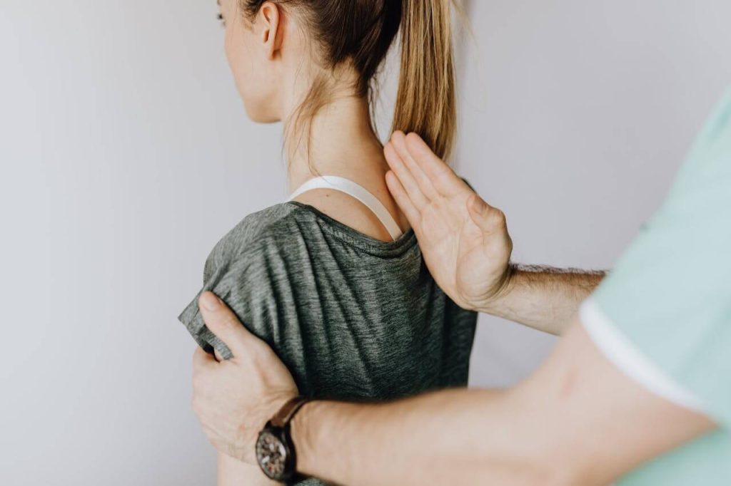 A physical therapist performing a back examination on a patient to assess injury and recovery progress.