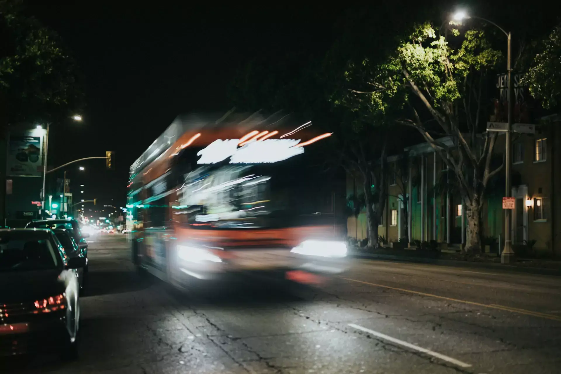 A blurred bus involved in an accident drives down a city street at night.