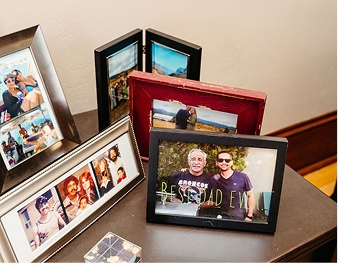 Una colección de fotografías familiares enmarcadas dispuestas en una mesa, incluyendo una foto de dos hombres con la leyenda «El mejor padre de todos los tiempos» escrita a lo ancho, perfecta para responder a las preguntas más frecuentes sobre el Día del Padre.