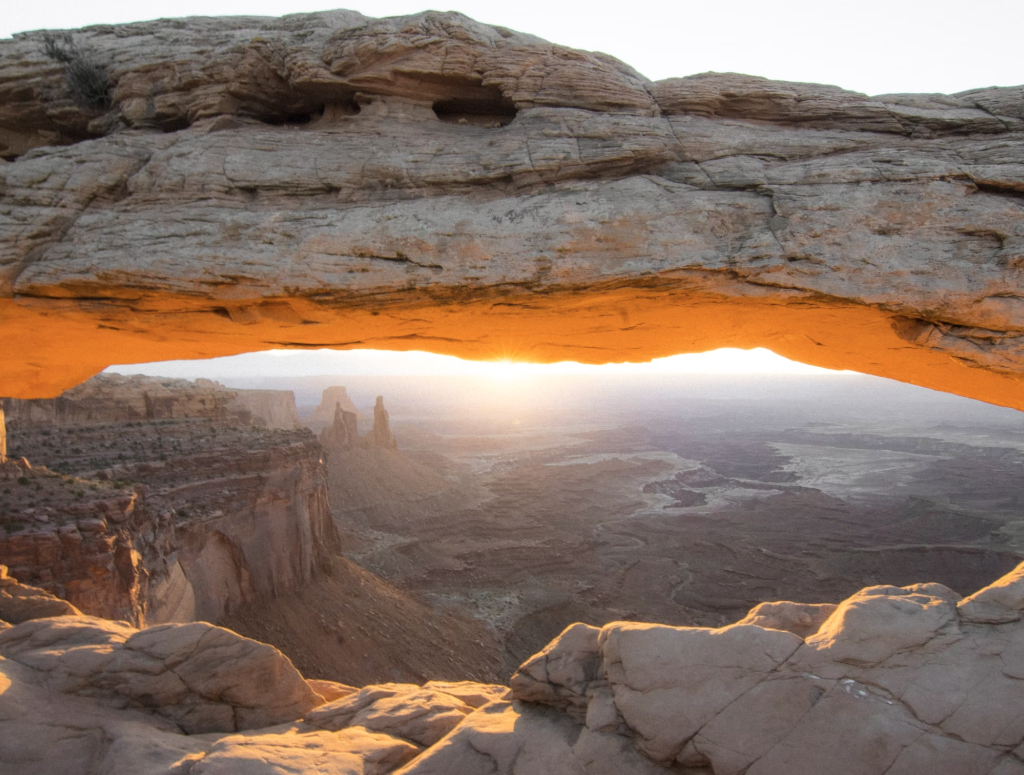 Sunrise viewed through the natural rock opening of Mesa Arch in Canyonlands National Park.