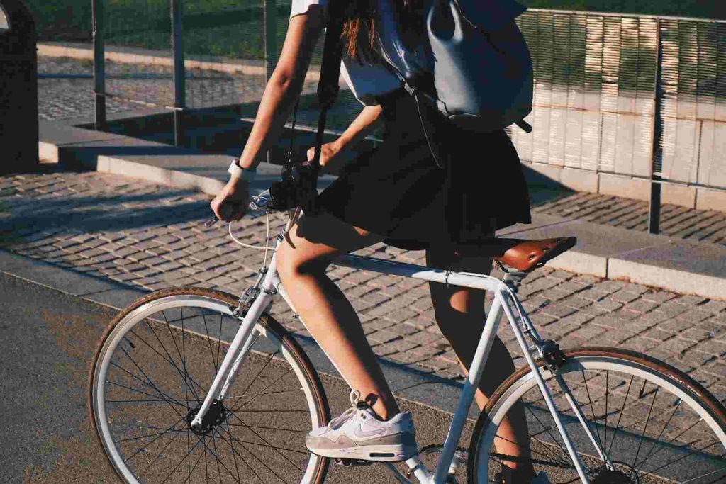 Un coche impacta contra una bicicleta (1) Una persona que monta una bicicleta blanca por un camino pavimentado justo antes de un accidente de bicicleta.