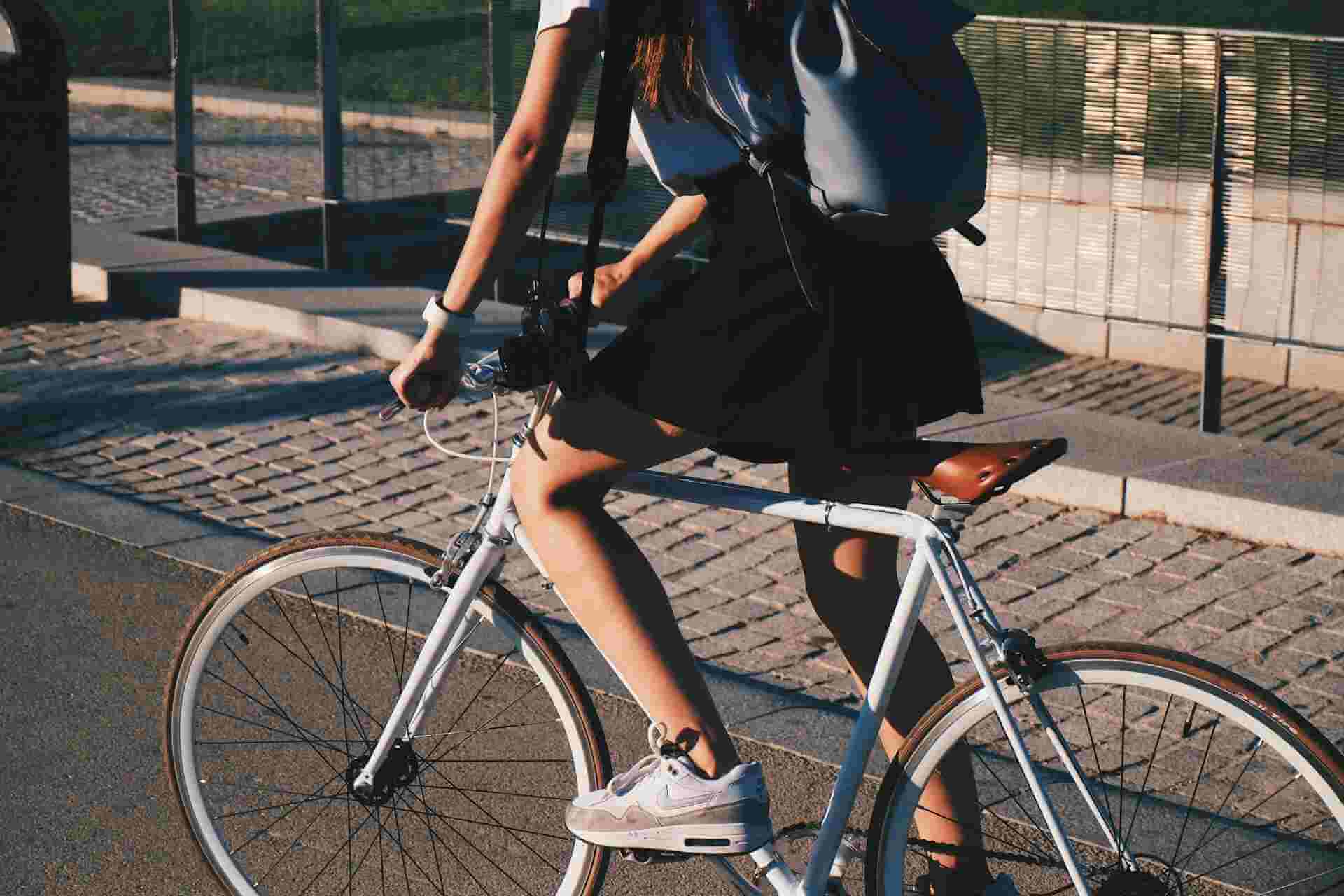Una persona que monta una bicicleta blanca por un camino pavimentado justo antes de un accidente de bicicleta.