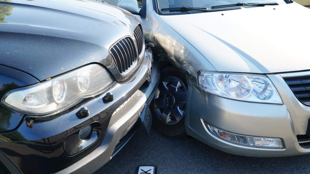 Two cars, a black SUV and a silver sedan, are involved in a minor collision.