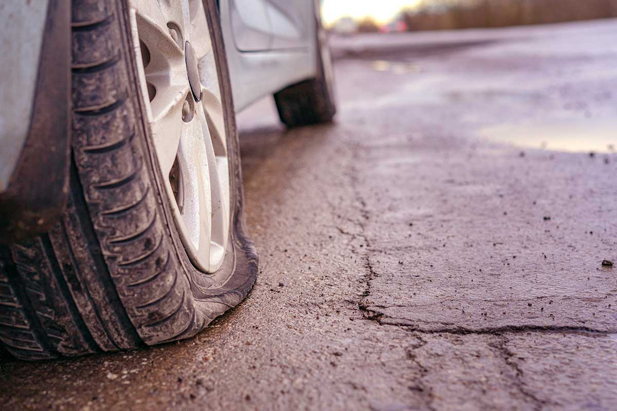 Un neumático de vagón que descansa sobre una carretera de asfalto con grietas.