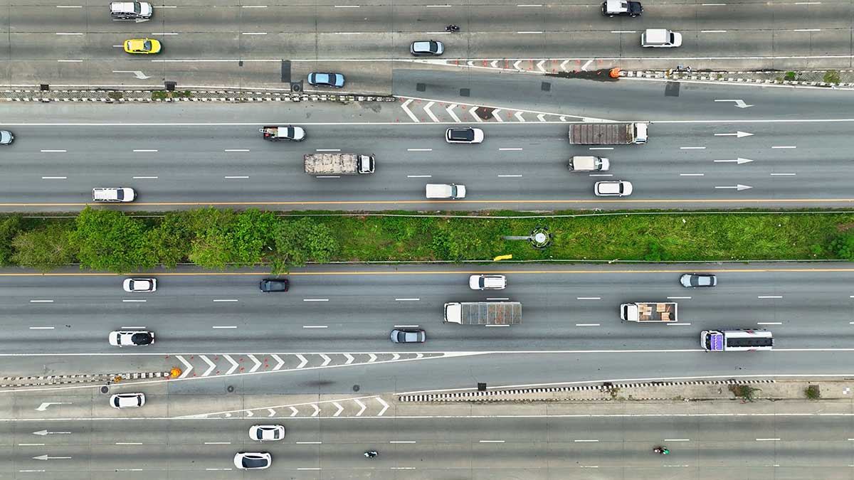 Aerial view of a multi-lane highway with traffic flowing in both directions, separated by a grassy median.