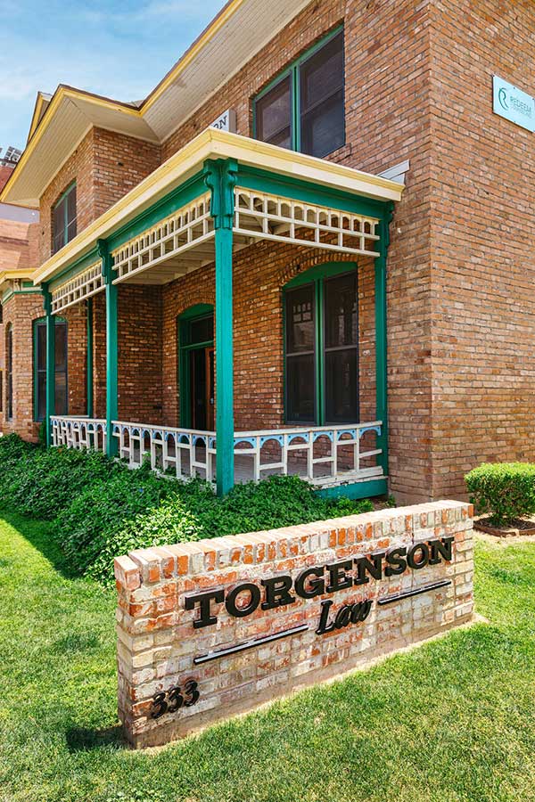 Brick building with a green porch and a brick sign in the front yard reading Torgenson Law 333, located in professional office areas.
