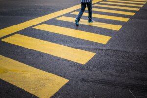 pedestrian walking (1) Pedestrian walking across a yellow-striped crosswalk on a paved street