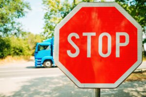 Red stop sign beside a roadway with a blue truck passing in the background